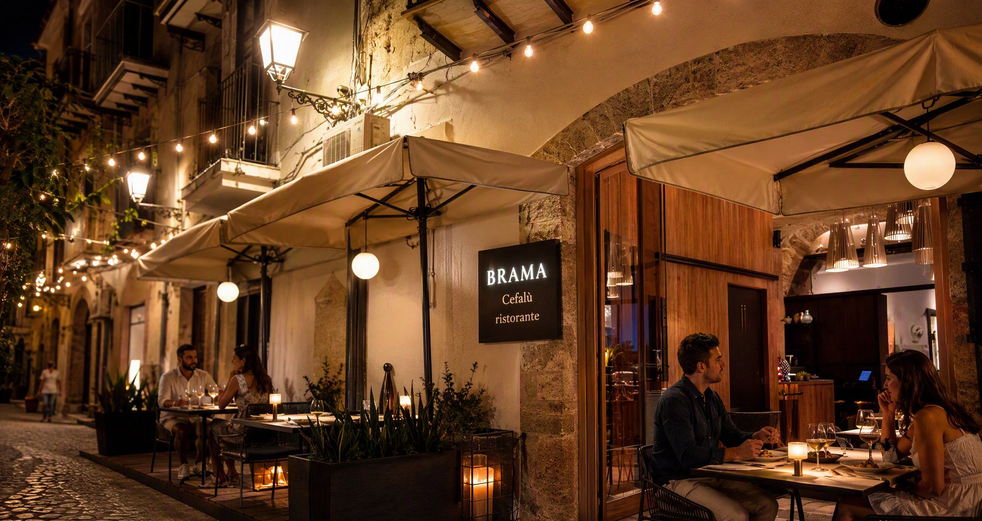 I tavoli all'aperto di Brama di sera, con l'insegna BRAMA Cefalù ristorante